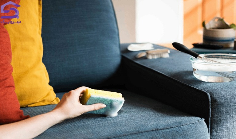 شست‌وشوی مبل پارچه‌ای با اسفنج و محلول شوینده ملایم در خانه